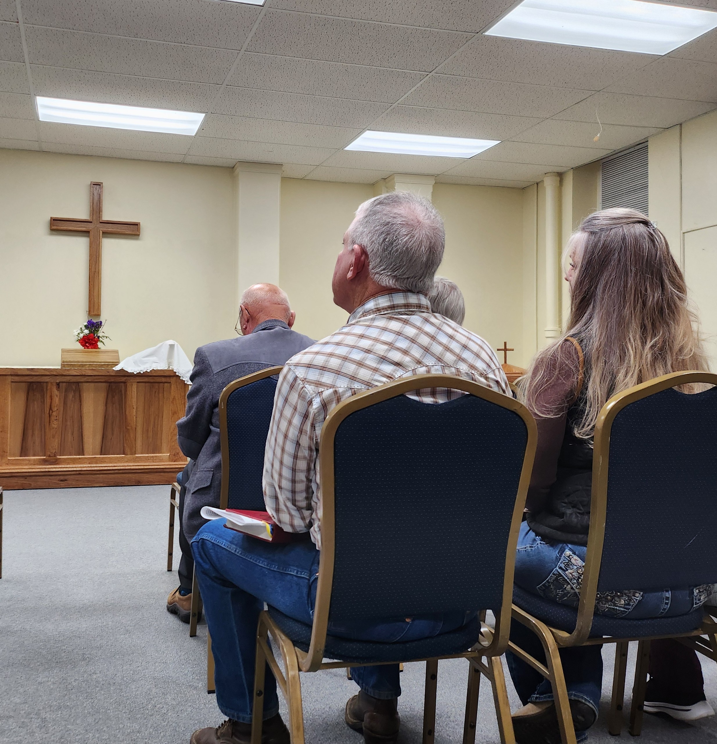 Some members of Christ the King listening to Pastor preach, with the altar visible in the background